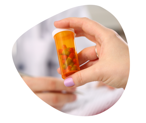 Eine rötlich transparente Tablettendose in einer Hand.