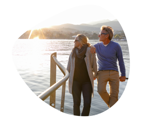 Ein Paar steht auf einem Steg und blickt über einen See in den Sonnenuntergang.