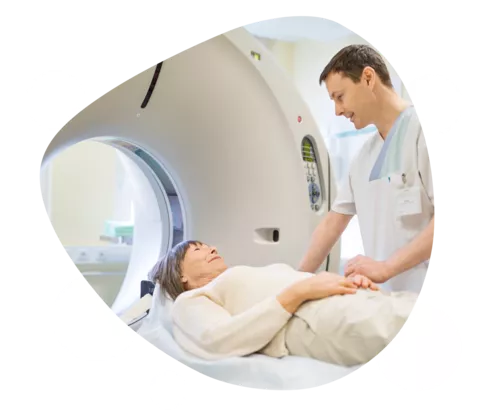 Eine Frau liegt auf dem Einschubtisch eines MRT, ein Mann steht daneben.
