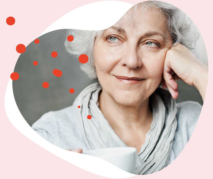 Leben mit Brustkrebs: Eine ältere Frau mit einer Tasse in der Hand schaut nachdenklich