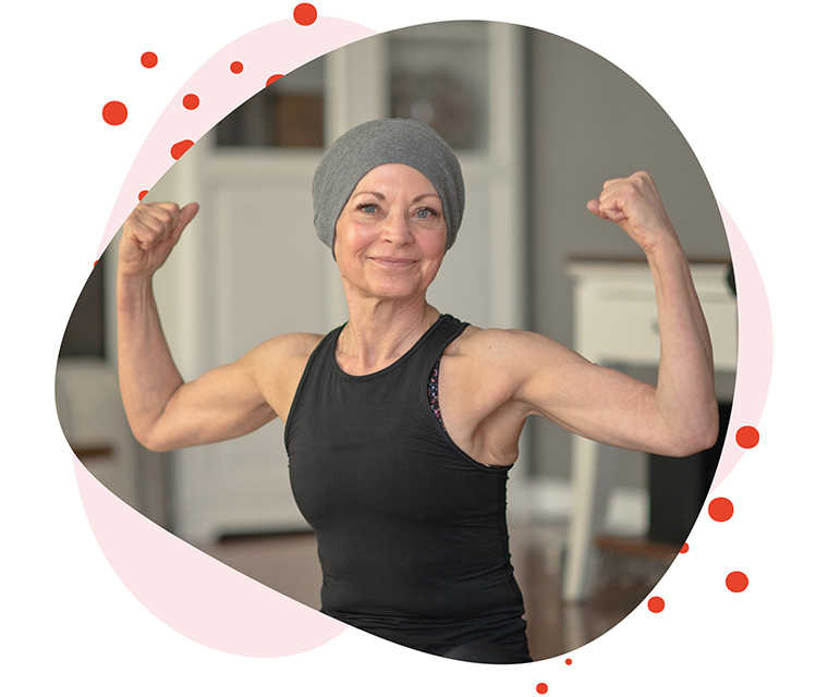 Leben mit Brustkrebs: Brustkrebspatientin zeigt ihre Armmuskeln und lächelt in die Kamera