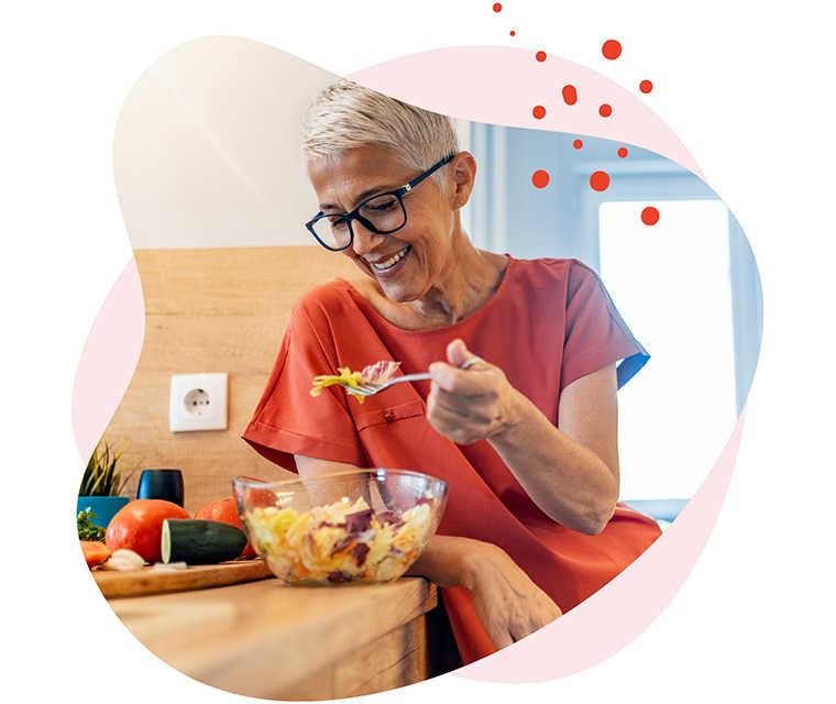 Leben mit Brustkrebs: Eine Frau steht in der Küche und isst einen Salat