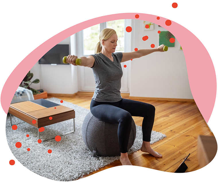 Leben mit Brustkrebs: Eine Frau absolviert Hanteltraining auf einem Gymnastikball Leben mit Brustkrebs: Eine Frau absolviert Hanteltraining auf einem Gymnastikball
