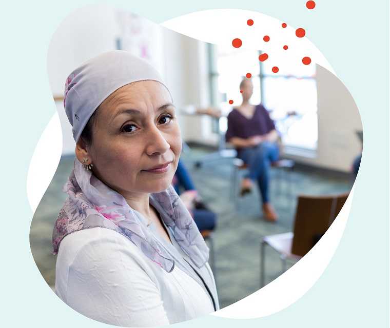 Leben mit Brustkrebs: Frau mit mit Kopftuch schaut aus ihrem Stuhlkreis in die Kamera