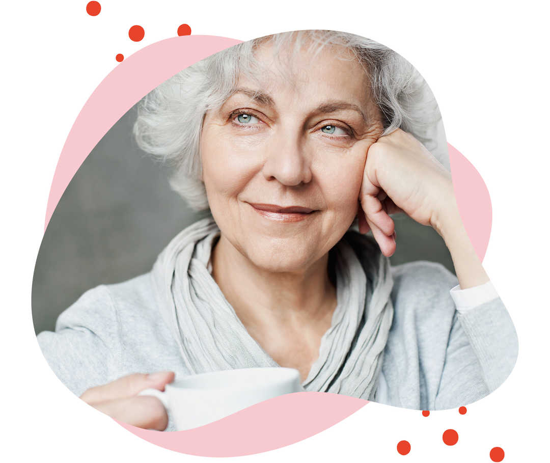 Leben mit Brustkrebs: Eine ältere Frau mit einer Tasse in der Hand schaut nachdenklich