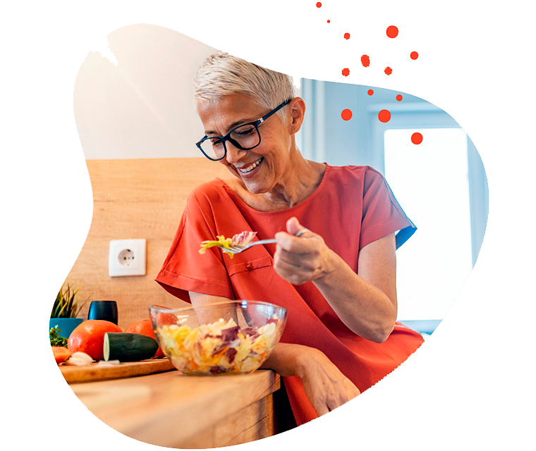 Leben mit Brustkrebs: Eine Frau steht in der Küche und isst einen Salat