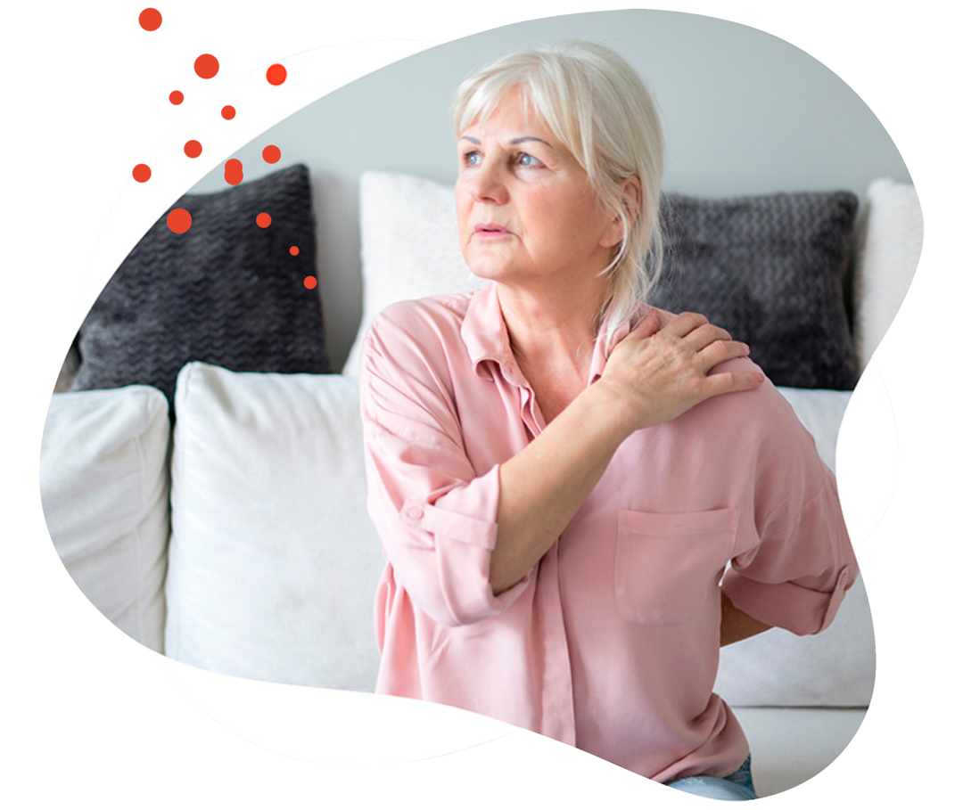 Leben mit Brustkrebs: Eine ältere Frau massiert sich ihre Schulter