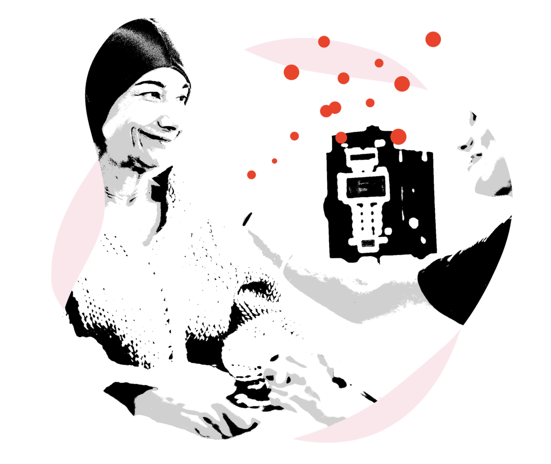 Eine Frau bekommt auf einem Behandlungsstuhl eitzend eine Injektion. Eine andere Frau hält ihre Hand und streicht ihr mit der anderen über den Oberamr