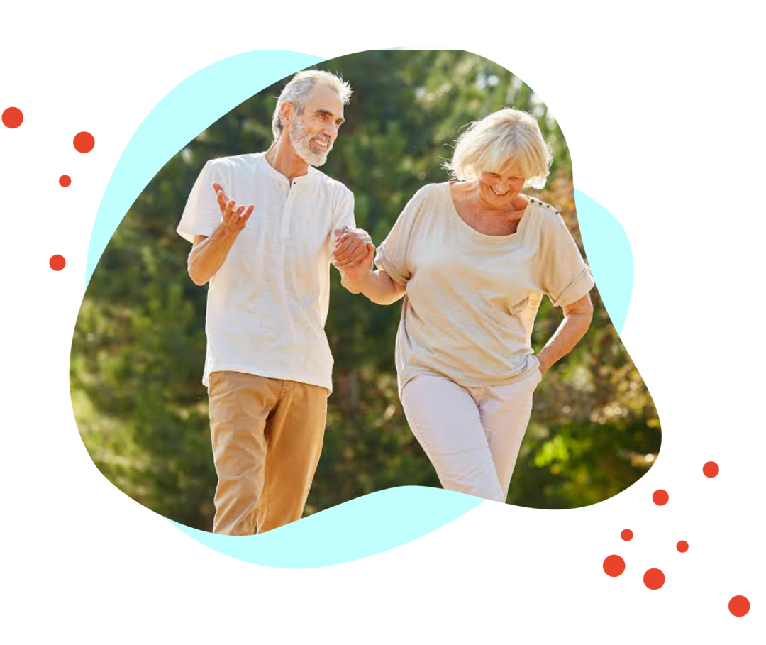 Eine Frau und ein Mann gehen Hand in Hand durch einen Park und freuen sich.