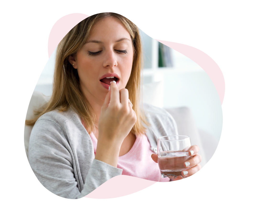 Eine Frau hält eine Tablette in der einen und ein Glas Wasser in der anderen Hand.